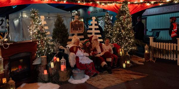 Santa Claus and Mrs. Claus pose with children in a festive Christmas setting.