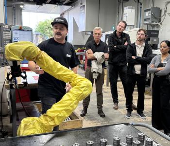 Mayor Siemens and tour participants examine one of the robotic arms that assists workers at Tiger Tool during a stop on the second annual Manufacturing Industry Tour.
